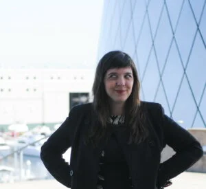 Marguerite Martin hands on hips in a black coat in 2015