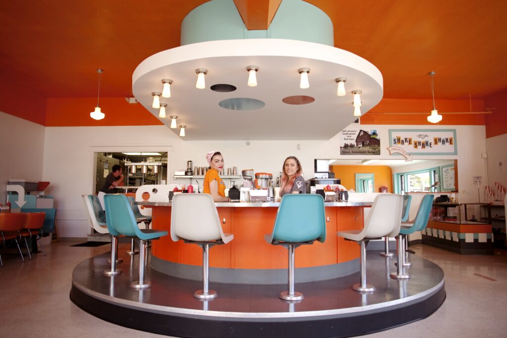 inside shake shake shake, blue and white chairs around a round bar while servers make shakes and tacoma's favorite burgers