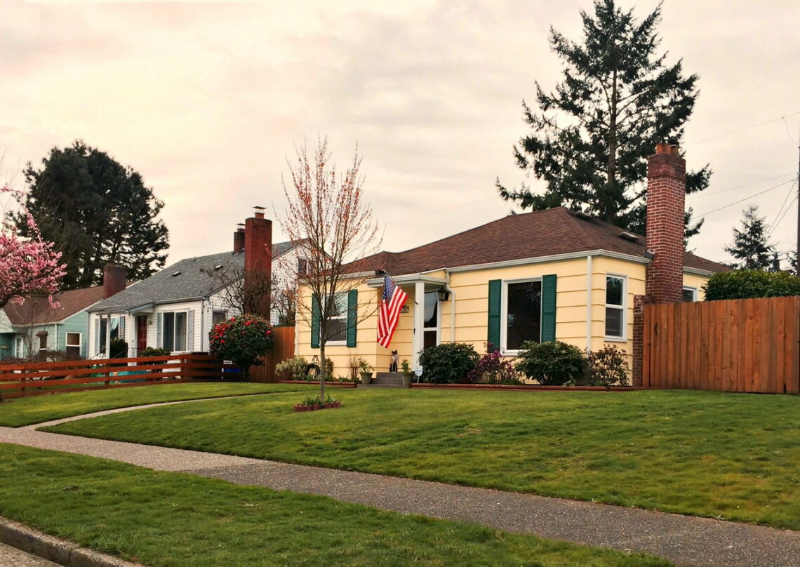 Yellow house with green shutters and an american flag in central tacoma WA