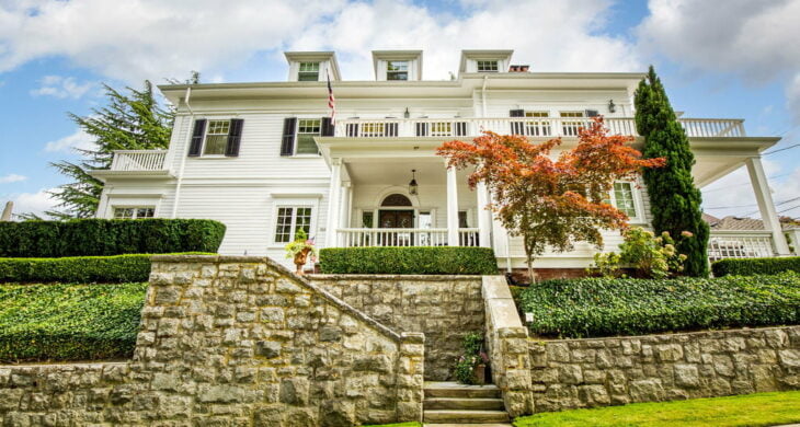 a white house on a hill above a rock wall in tacoma's stadium district