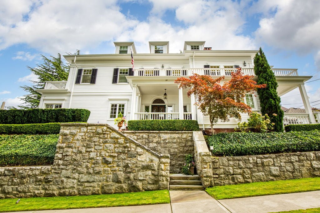 a white house on a hill above a rock wall in tacoma's stadium district