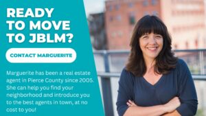 A photo of JBLM real estate agent marguerite martin with her arms crossed in front of a building in Tacoma, Washington with the words, "Ready to move to JBLM? Marguerite has been a real estate agent in Pierce County since 2005. She can help you find your neighbohood and a real estate agent to help you."