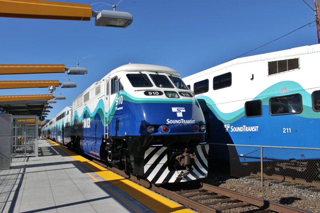 A photo of two Sounder commuter trains. One facing north and one facing south. Sounder trains help people commute from Tacoma to Seattle and back.