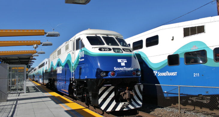 A photo of two Sounder commuter trains. One facing north and one facing south. Sounder trains help people commute from Tacoma to Seattle and back.