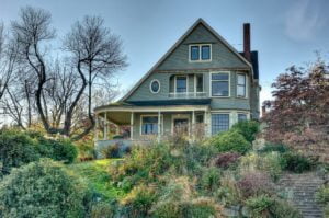 a photo of a green victorian home surrounded by floral landscaping, chinaberry hill in tacomas stadium district