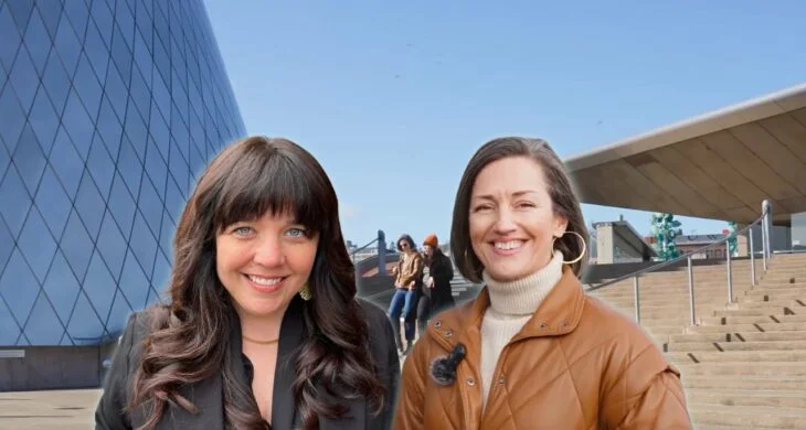 A screenshot of two people one with long dark hair one with short brown hair standing in front of the glass museum in downtown tacoma washington.