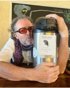 Tobin Ropes from Mad Hat Tea in Tacoma WA holds a tea thermos and gives it a kiss