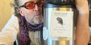 Tobin Ropes from Mad Hat Tea in Tacoma WA holds a tea thermos and gives it a kiss