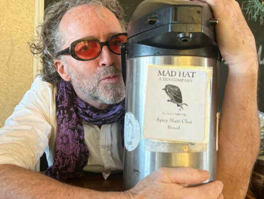 Tobin Ropes from Mad Hat Tea in Tacoma WA holds a tea thermos and gives it a kiss