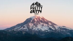 A Photo of Mt Rainier at sunrise with the logo for "Pretty Gritty Tours" above the mountain in Tacoma Washington
