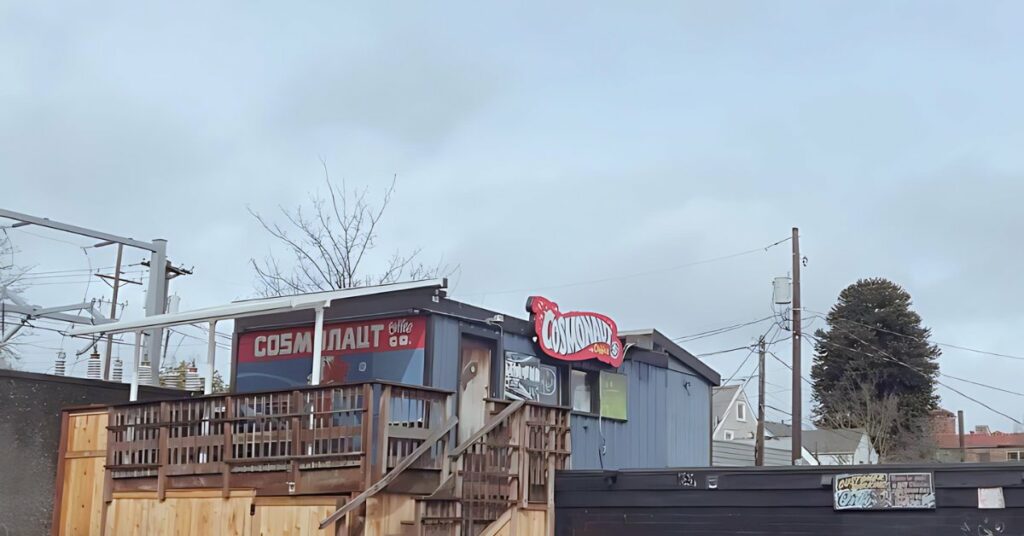 the exterior of local coffee shop Cosmonaut Coffee in Tacoma Washington's Stadium District and North Slope neighborhood. The shop is located on the roof up some stairs from Supernova and a red sign with white letters says, "Cosmonaut"