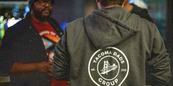 Two people talk together at a meetup of the Tacoma Dads Group in Tacoma Washington. One person wears a hoodie that says 