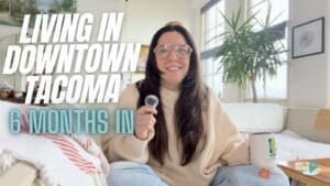 Tacoma real estate agent Marguerite Martin sits on a sofa with legs crossed with the words "Living in Downtown Tacoma: 6 months in"
